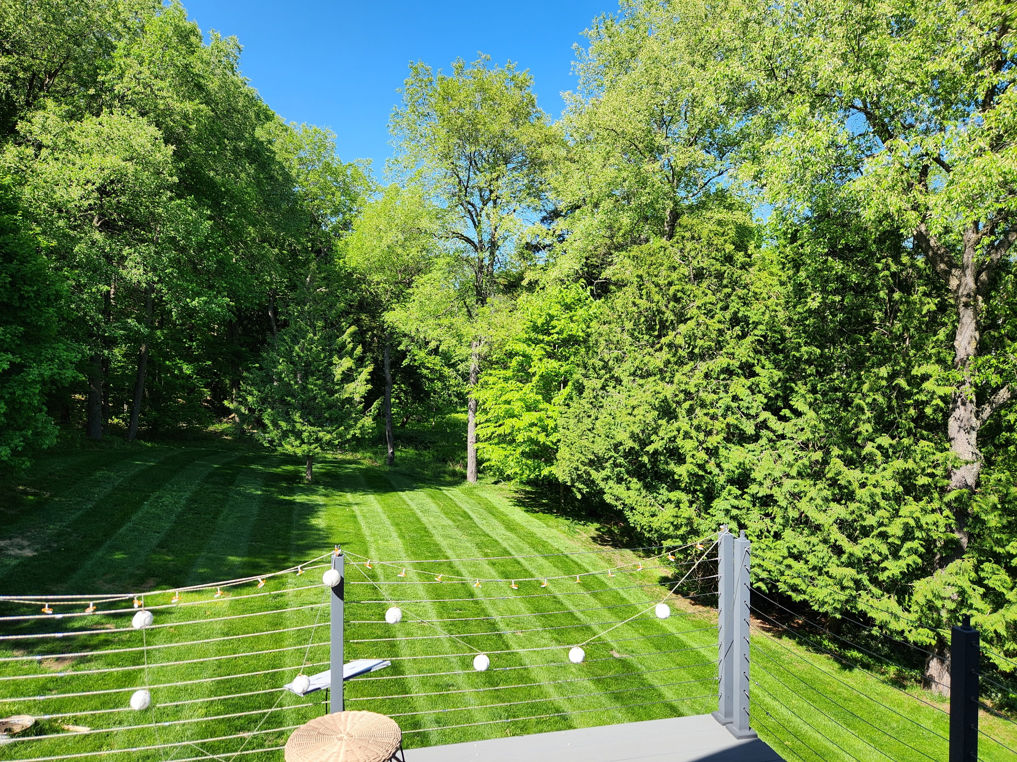 Striped backyard lawn with string lights, viewed from a deck
