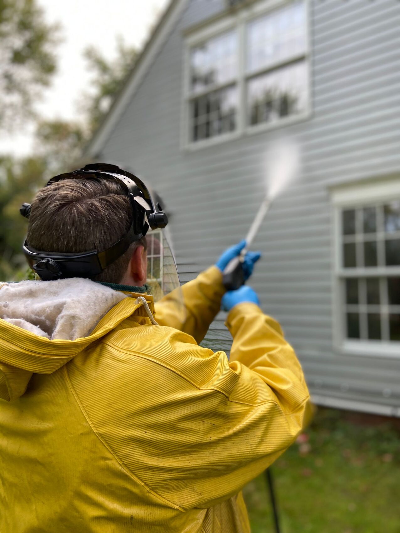 Pressure washer cleaning the exterior siding of a house